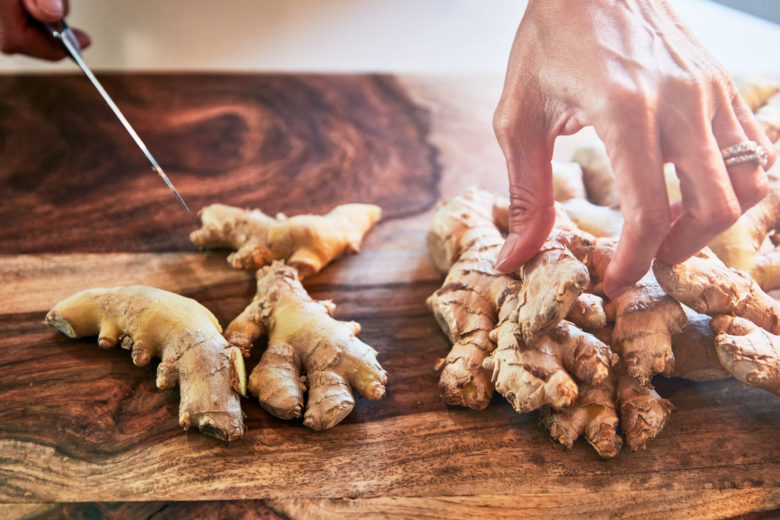 chef hands in a kitchen chopping ginger on a wooden chopping board