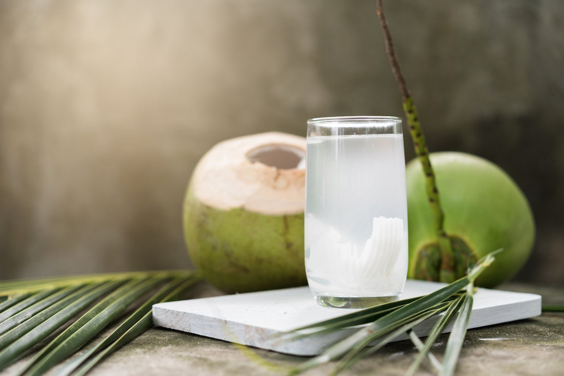 coconut water in a glass with coconuts in the background