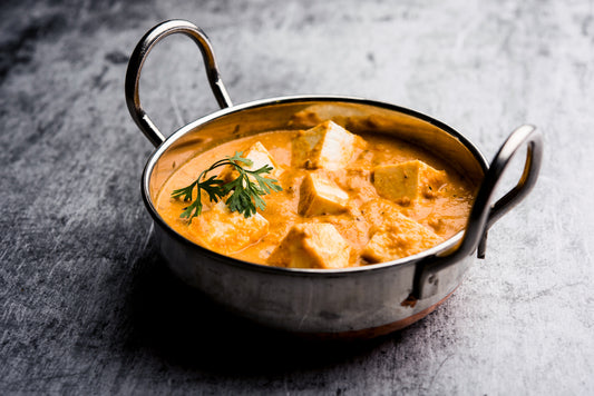 metal bowl with turmeric curry on a grey background