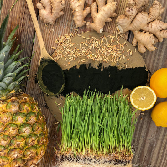 wheatgrass lemon pineapple ginger and spirulina on a wooden table KOR Shots green up ingredients